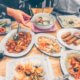 Table full of Thai food with hand reaching for rice